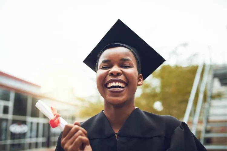 a graduate smiling while holding her degree